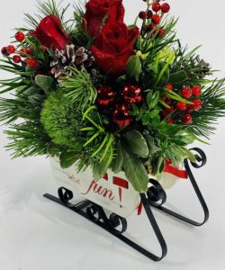 roses and red berries with seasonal greens in sleigh