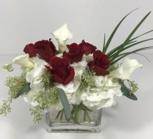 For that special someone on that special occasion - this arrangement will certainly delight. A half dozen red roses, hydrangea and white calla lilies in a clear contemporary rectangle vase.
